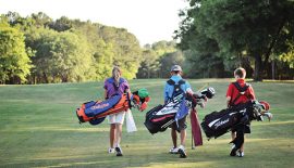 One girl and two boys walking the course with their bags.